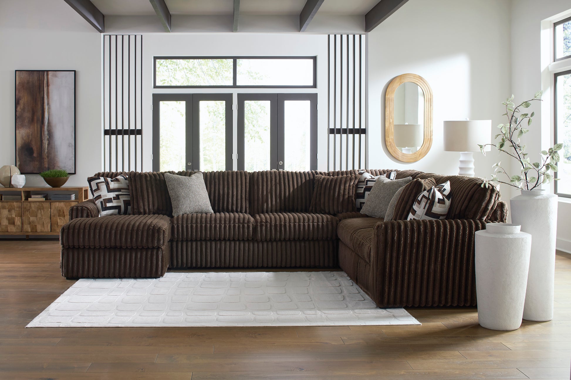 Brown sectional sofa in a modern living room with large windows and decorative elements.