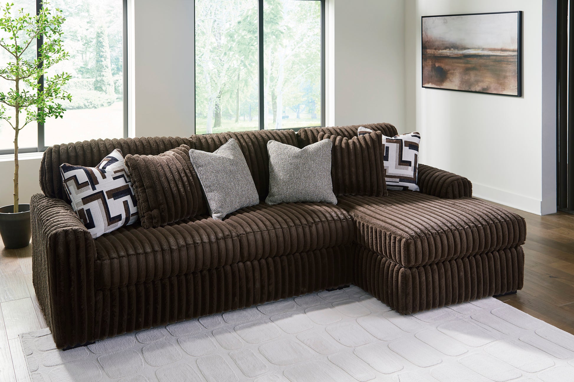 Brown sectional sofa with decorative pillows in a room with large windows.