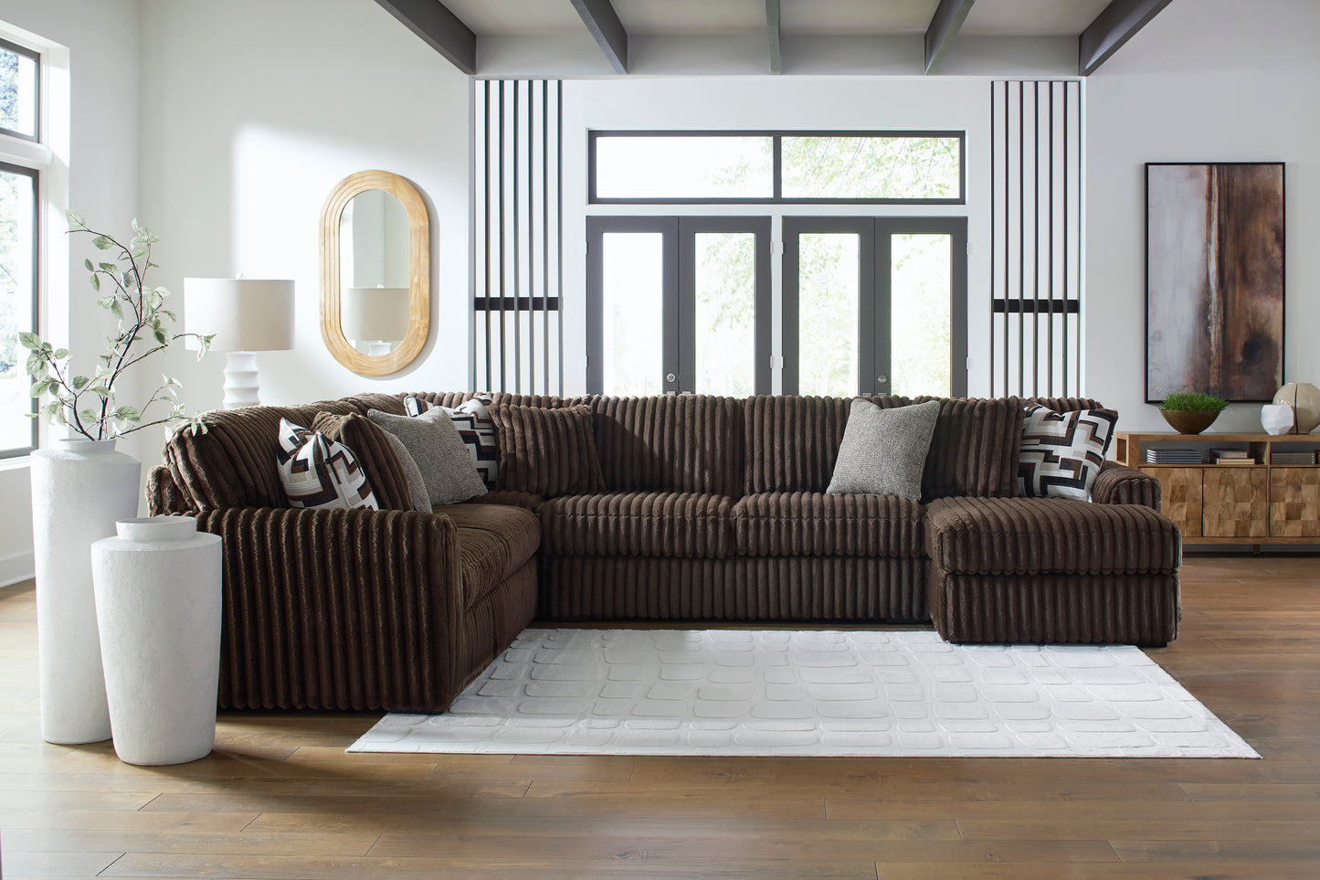 Brown sectional sofa in a modern living room with large windows and decorative elements.