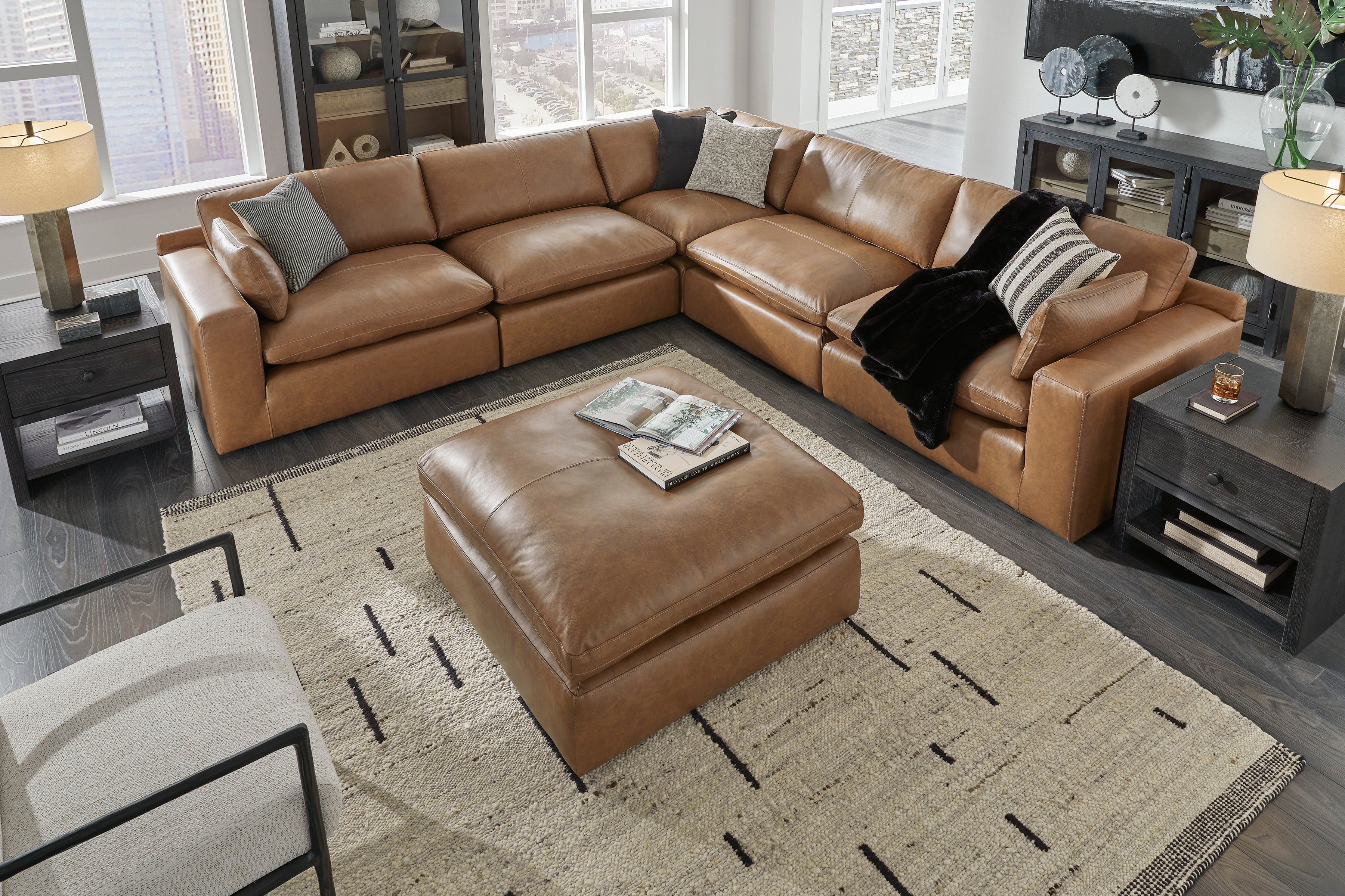 Brown leather sectional sofa with ottoman in a living room setting.