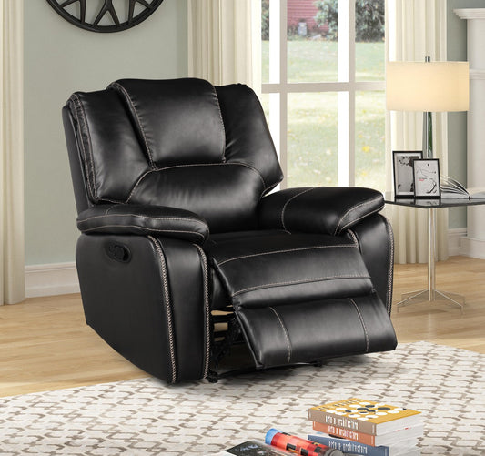 Black leather recliner chair in a living room setting with books and remote controls on the floor.