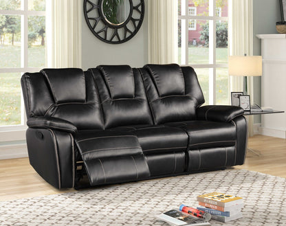 Black leather reclining sofa in a living room setting with books and a remote control on a coffee table.