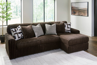 Brown sectional sofa with decorative pillows in a room with large windows.